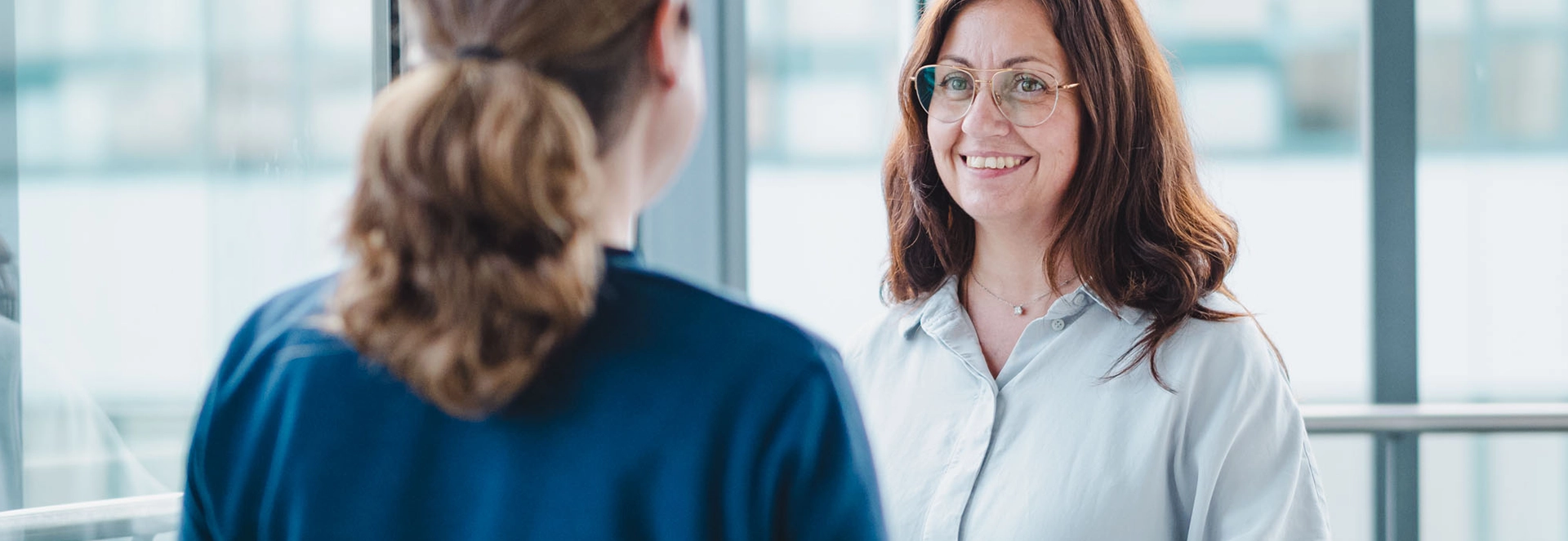 Zwei Mitarbeiterinnen im persönlichen Gespräch in einem modernen Büro